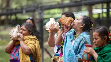 Indigenous Women performing a Tlalmanalli opening ceremony. They are wearing traditional dress and blowing into sea shells.