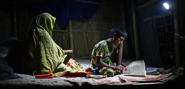 A girl studies under the light of a rechargeable solar lamp