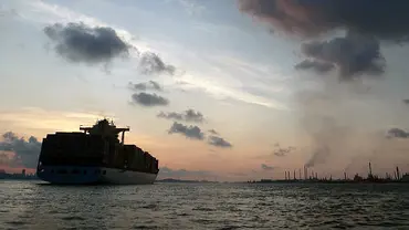 A container ship looms imposingly against a brilliant skyline