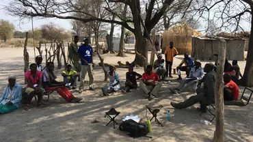 A group of men and women gathered under some trees