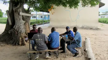 A group of men at a table under a tree