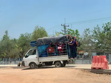 Pick-up van packed with people and suitcases.