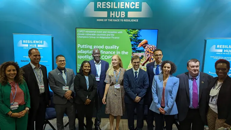 A group of men and women pose for a photograph in a line, with the words 'Resilience Hub' behind them.