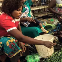 Woman reaches out to green pile of beans / Fresh vegetables on display for sale at Lusaka City Market, Lusaka. (Photo: copyright Salim Dawood)
