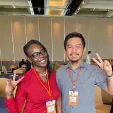Two people posing for a photo doing the V peace sign with their fingers.