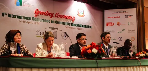 A row of women and men sit at a table looking out at an audience.