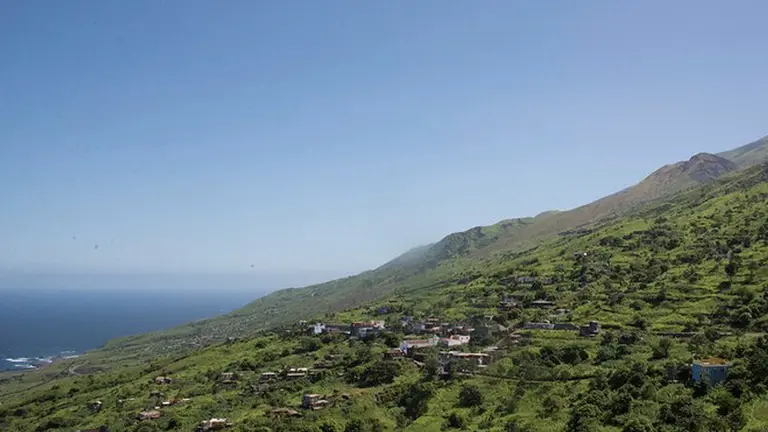 View of a large hill and the sea on the left.