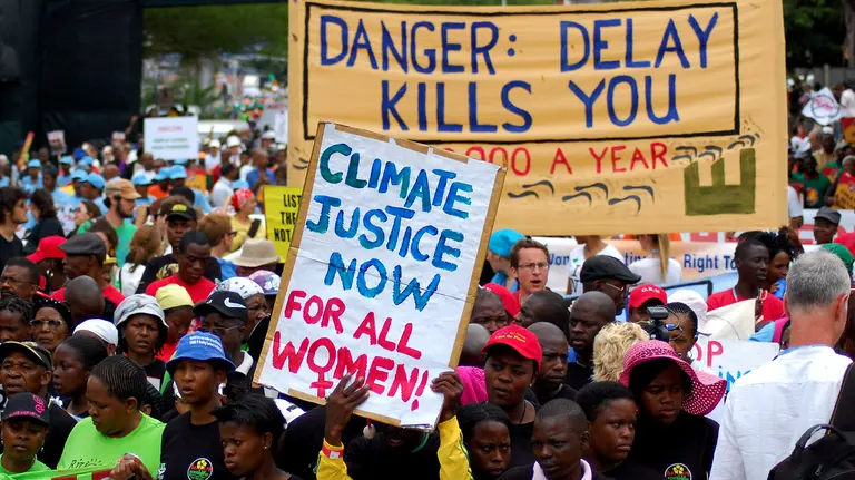 A host of people carrying placards and banners, with a prominent banner that says: "Danger: delay kills you".