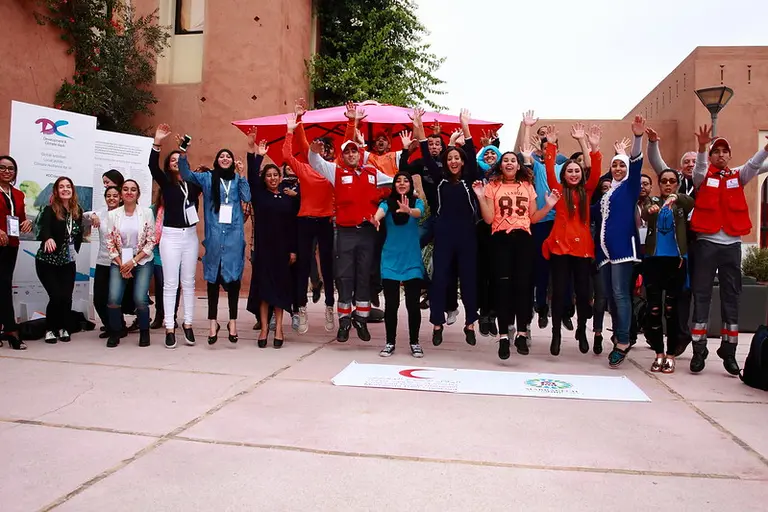 A group of people jumping in the air smiling, with their arms up.