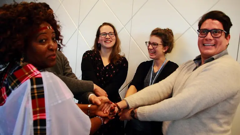 A group of people standing next to each other holding hands in the centre