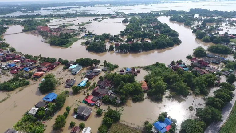 Aerial view of a flooded village. Only roofs and vegetation are visible.