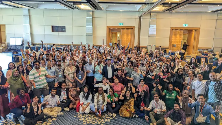 Huge group of people smiling and putting their hands up