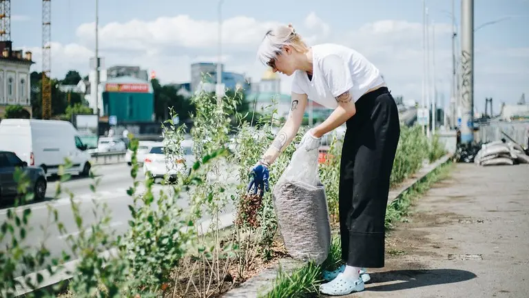 A woman is sowing seeds on the side of the road.
