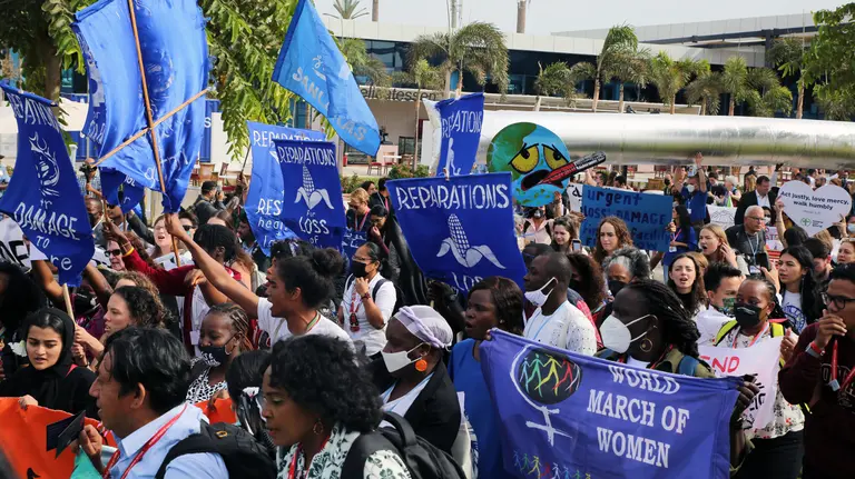 A crowd of mainly women march carrying protest banners. 