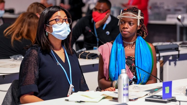 Two women, one wearing a face mask, at a conference.