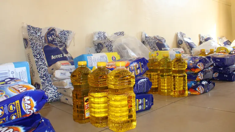Cooking oil bottles and cleaning products are stacked neatly on the floor ready to be distributed to those in need. 