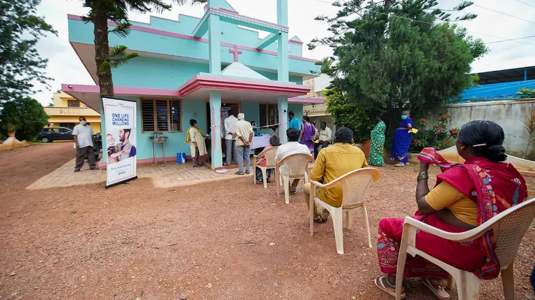People in chairs socially distance themselves in a queue