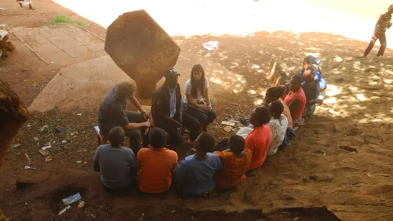 Group of people sitting on the floor, discussing research in Kibera