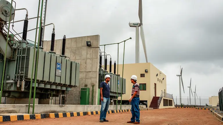 Two men standing in front of wind turbines.