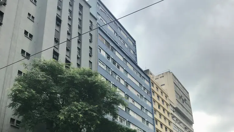 A tall building on a street with trees in the front.