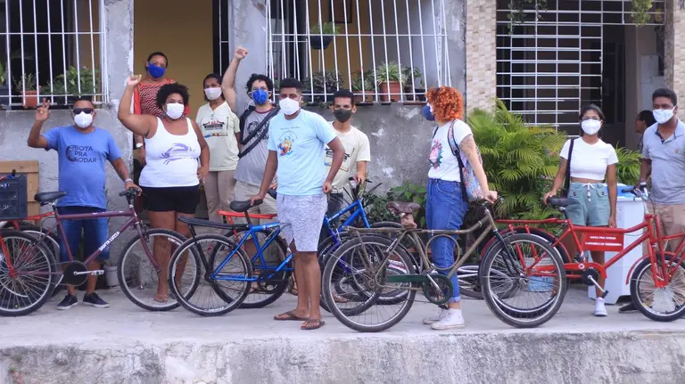 A group of people wearing masks standing beside bicycles.