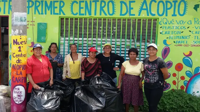 A group of individuals stand with barbage bags.