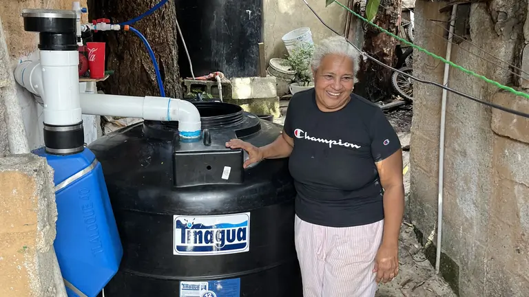 A woman standing next to a black water tank.
