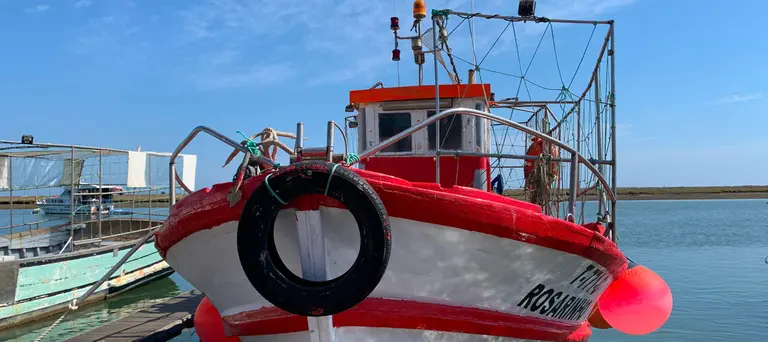A fishing boat moored against a pier.