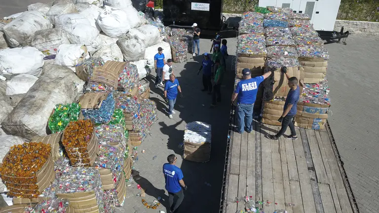 A group of men working, standing around boxes filled with garbage.