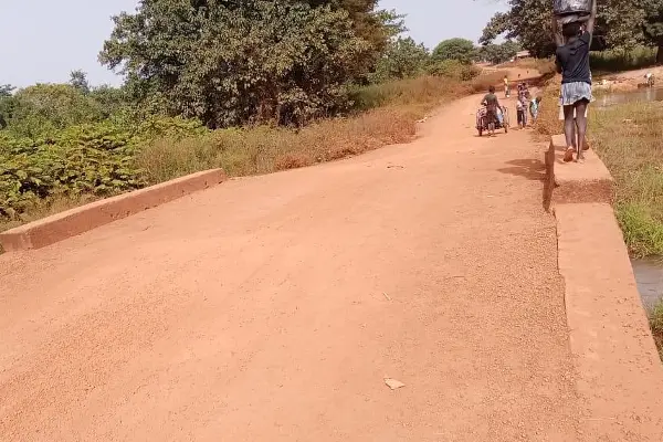 A woman carries water over a bridge.