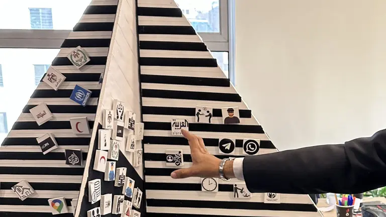 A pyramid-type structure made of foam upon which people have stuck small cubes representing ideas. 