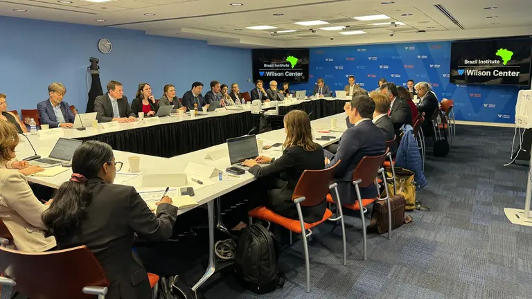 A group of people sit around a conference table talking.