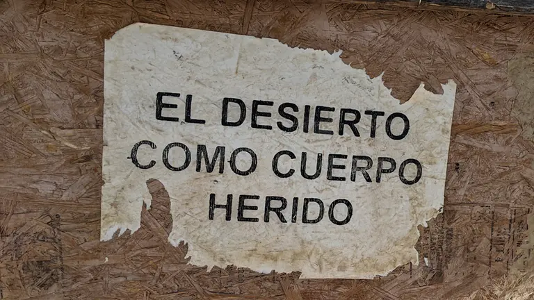 A sign with the words "El desierto como cuerpo herido"