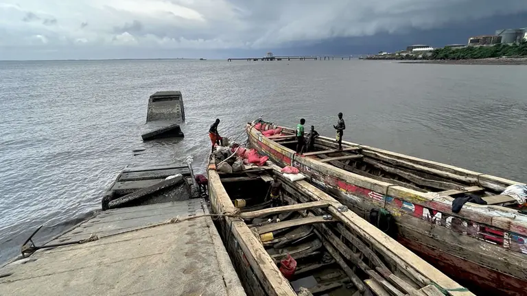 A large boat at a jetty, with several people in it.