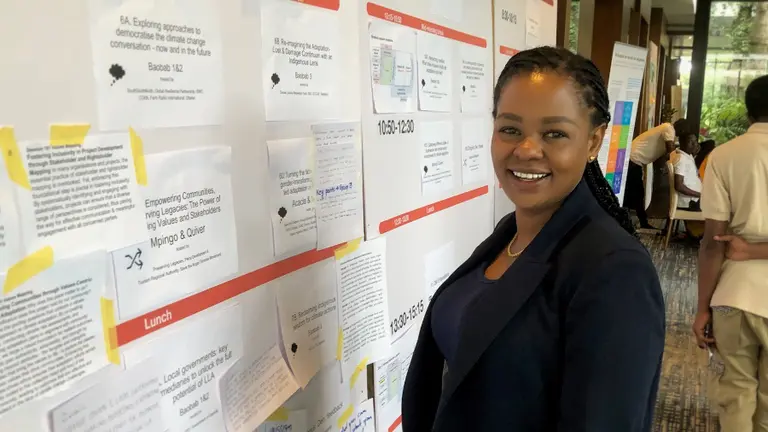 A woman standing in front of a noticeboard smiling.