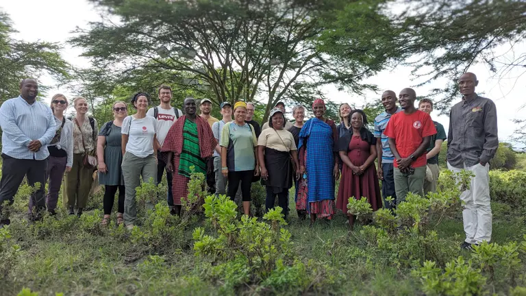 A group of people standing in front of big trees.