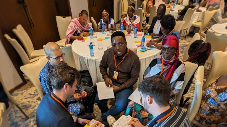 Groups of people in seated at round tables and talking.