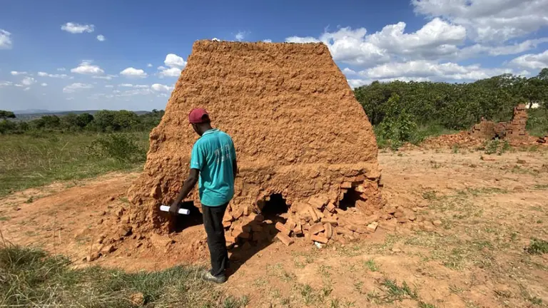 A man stands in front of a pile of clay.
