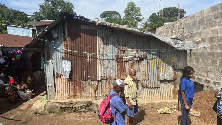People standing outside a corrugated iron house.