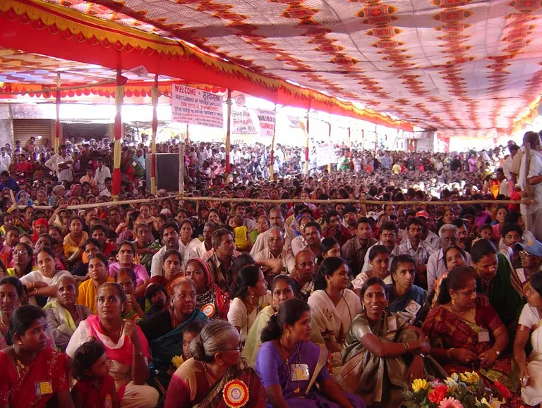 A vast crowd of women gather under a colorful covered canvas roof. 