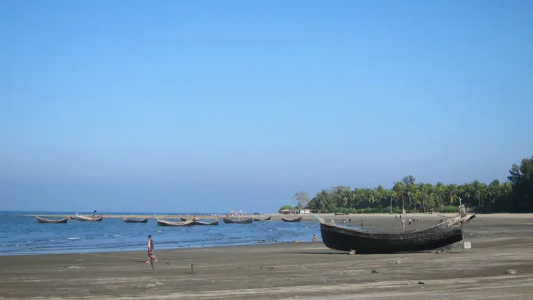 Small fishing boats just off the coast. Another boat on the beach in the foreground.