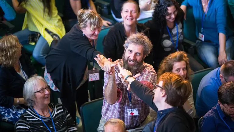 Pablo Suarez celebrating with colleagues by high fiving at a conference