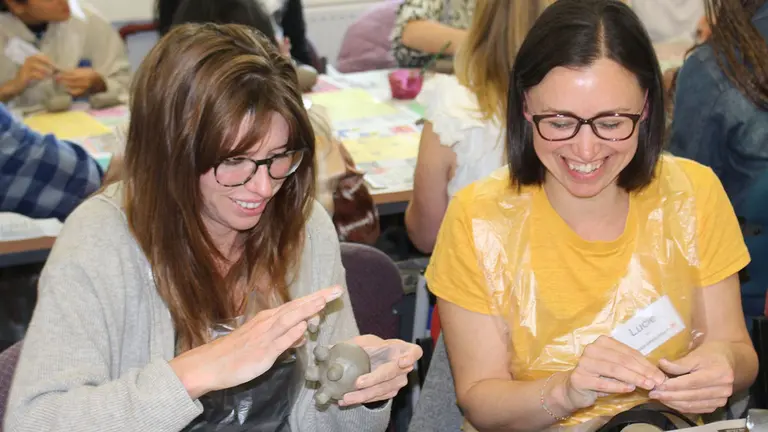 Two staff members enjoy painting some pottery during the IIED retreat in 2024.