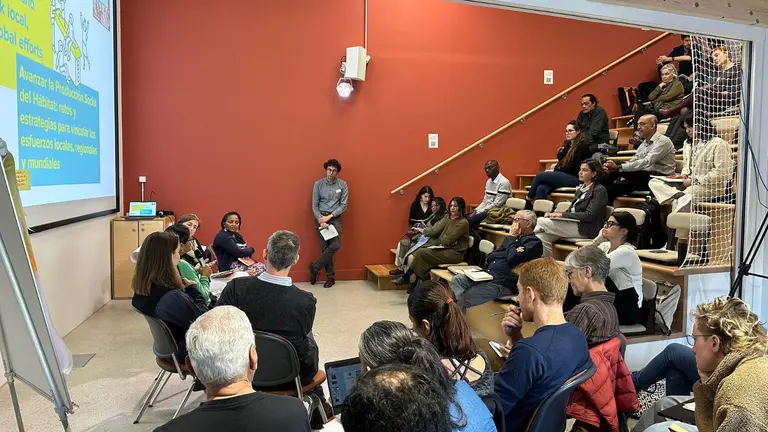 Group of people sitting on chairs while speakers are presenting using PowerPoint.