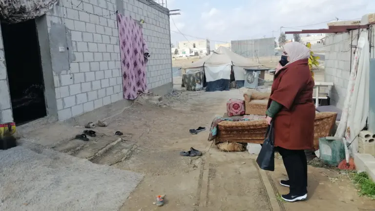 A woman stands outside a house.