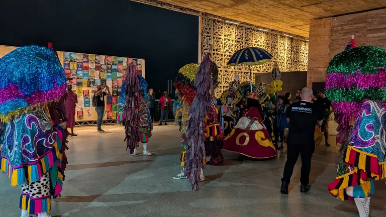 People dressed in colourful costumes dancing to local music.