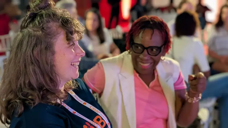 Two women sitting down, laughing and talking.