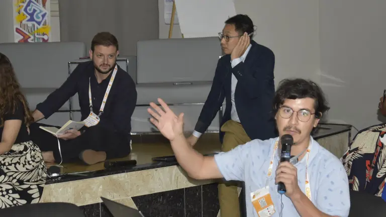 One person presenting using a microphone while others listen.