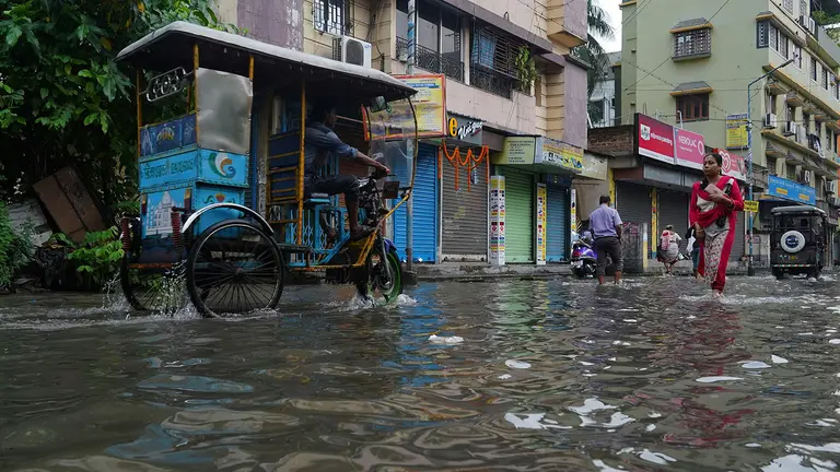 A rickshaw tries to make progress down a flooded street.