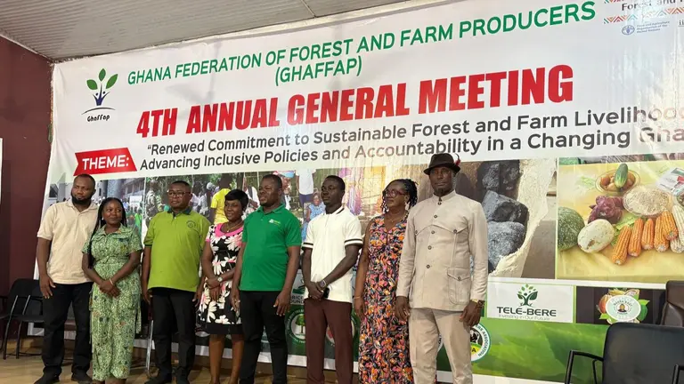 People dressed in colourful shades of green, pink and brown posing for a group photo in front of a conference banner.